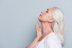 Close up profile with copy space of nice charming aged woman touching her skin of neck with hand