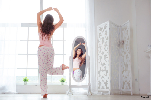 Young women realizing her liposuction results while recovering at home.