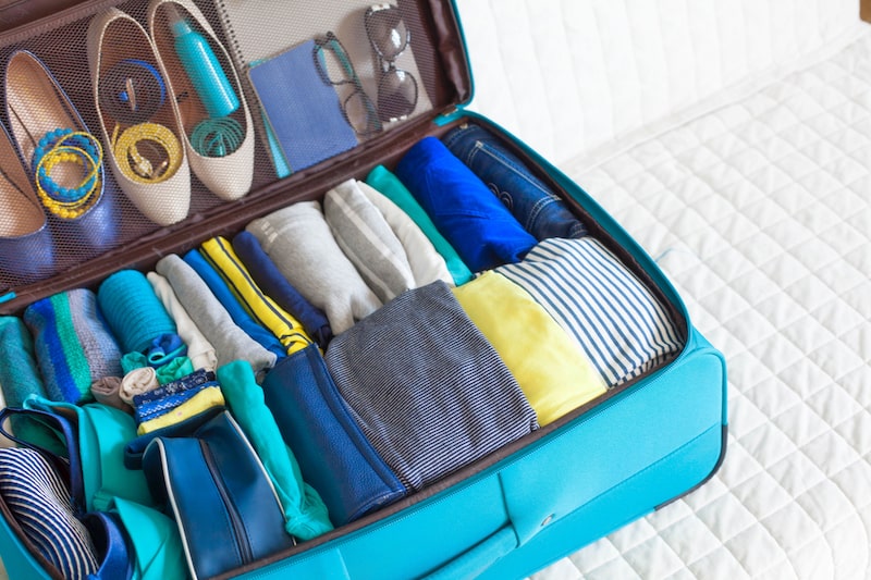 Full suitcase holding blue and yellow clothes.