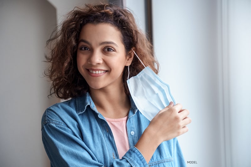 Woman taking off her COVID face mask