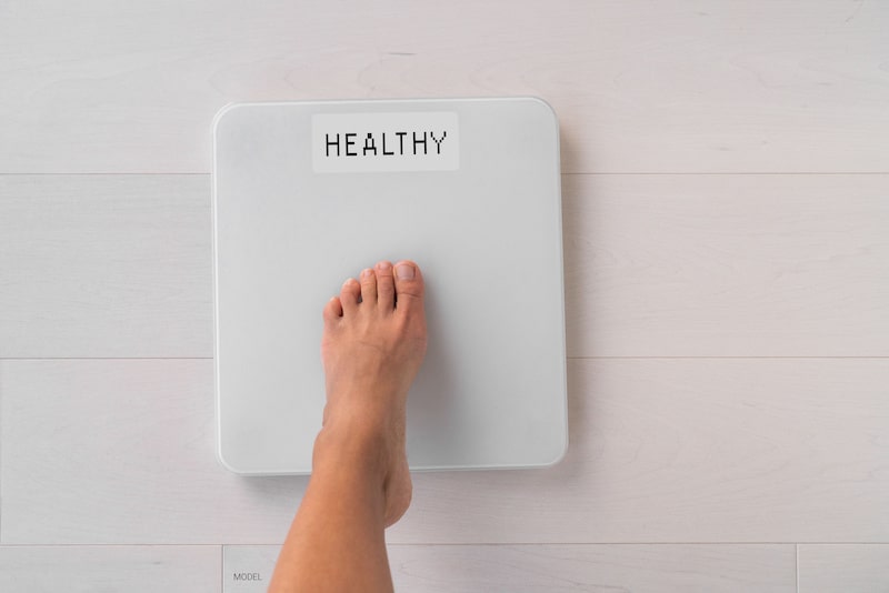 Foot stepping on scale showing a healthy body weight.