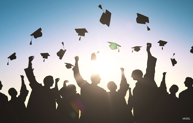 Silhouette image of recent graduates throwing their caps in the air