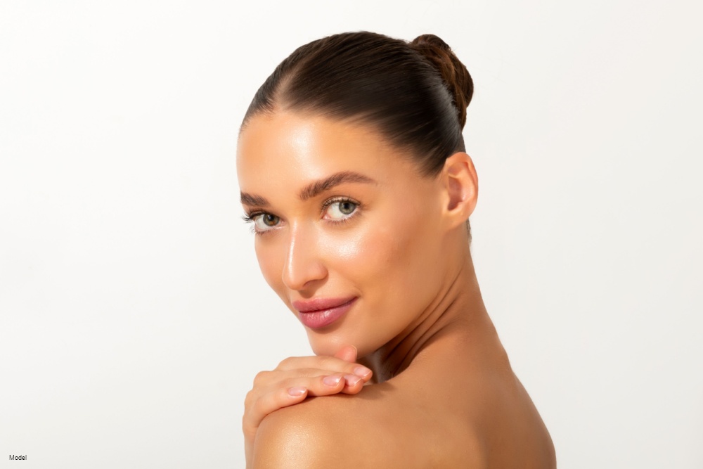 Portrait of elegant young woman with smooth, clear face skin, posing against white studio background. 