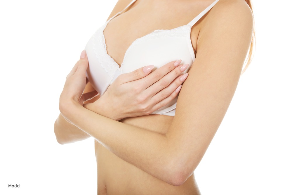 Woman in white bra, arms crossed over chest, white background
